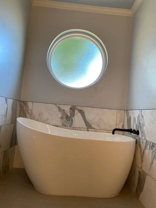 Freestanding soaking tub under a round window